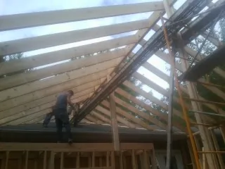 Rafters going up over a new addition with a worker on the wall in Winfield