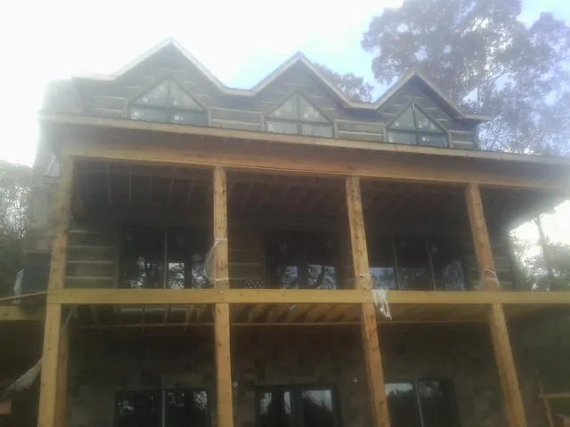 Dormers and porch framing on a large log home under construction — Roof Coating work by our crew in Winfield